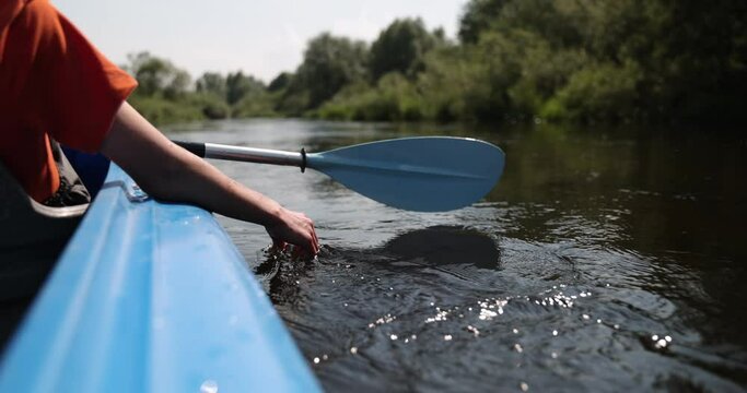 A man, boy puts fingers down in river kayaking. Kayaking on the river, unity harmony nature on the river. Slow Motion