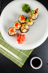 tempura sushi roll with salmon and tobiko caviar on a white plate