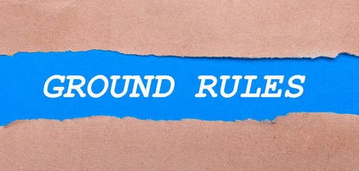A strip of blue paper with the inscription GROUND RULES between the brown paper. View from above