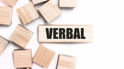 On a light background, wooden cubes and a wooden block with the text VERBAL. View from above