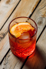 classic negroni cocktail with orange slice in a glass on a wooden background with lines