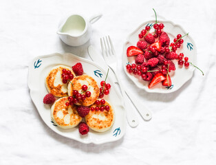 Syrniki with red currant, raspberry and sour cream on the light   background, top view. Delicious breakfast, brunch
