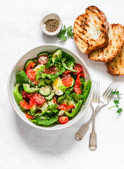 Delicious Mediterranean salad with salmon, egg, vegetables, lettuce on a light background, top view