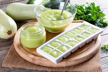 Zucchini puree in ice cube trays ready for freezing on a cutting board on a table. Frozen Food Concept.