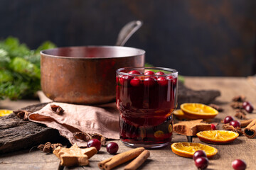  Hot mulled red wine drink with citrus, apples, cinnamon sticks, cloves and anise in cooking pan on wooden background