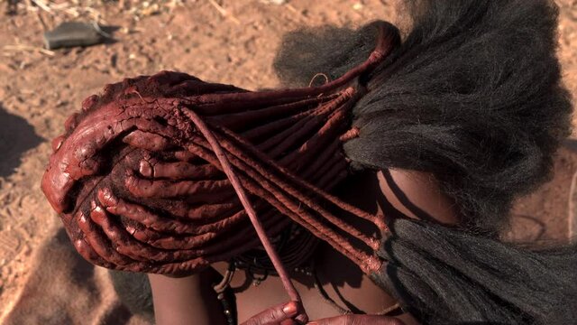 Closeup shot of Himba woman doing her hair at traditional Himba village near Kamanjab in northern Namibia, Africa.