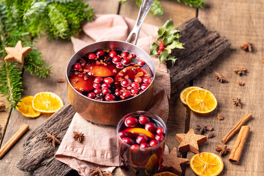  Hot mulled red wine drink with citrus, apples, cinnamon sticks, cloves and anise in cooking pan on wooden background