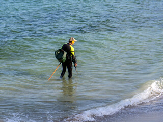 treasure seeker at sea with a metal detector