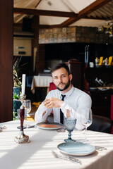 A young bearded male businessman is sitting at a table in a fine restaurant and waiting for his order. Customer service in the catering.