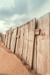 Worn wooden fence on sandy beach, vertical image