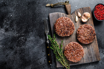 BBQ grilled beef meat patties for burger from mince meat and herbs on a wooden board. Black...