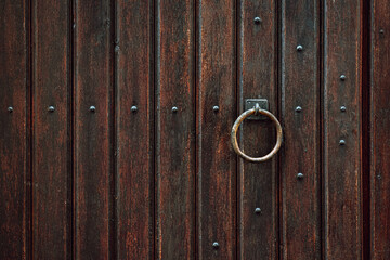 Fototapeta premium Wooden door with iron handles. Ancient wooden door. Detail of a wooden background.