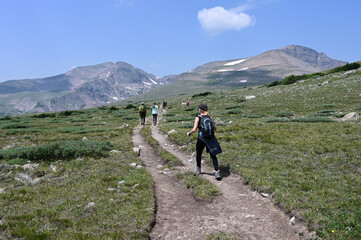 Hikers on trail in alpine tundra above St Mary's Glacier and above treeline in Arapaho National Forest, Colorado on sunny summer morning.