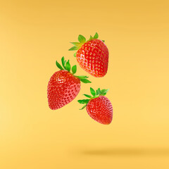 Fresh raw ripe strawberry with green leaves falling in the air, food levitation