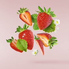 Fresh raw ripe strawberry with green leaves falling in the air, food levitation