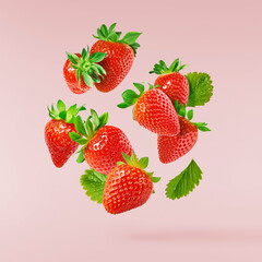 Fresh raw ripe strawberry with green leaves falling in the air, food levitation
