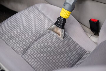 Man car detailing studio worker cleaning car textile upholstery with vacuum washer