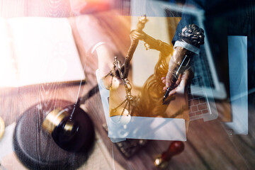 Justice and law concept.Male judge in a courtroom with the gavel, working with, computer and docking keyboard, eyeglasses, on table in morning light