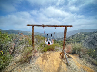 Boy having fun swinging in a hammock outdoors with oceanfront view in Malibu, California