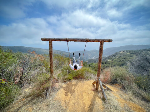 Boy having fun swinging in a hammock outdoors with oceanfront view in Malibu, California