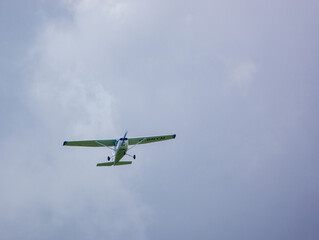 Fototapeta na wymiar G-BNYM Cessna 172N Skyhawk (172-73854) a 4-seat, single engine, high wing light aircraft flying low overhead in a light cloud blue and white sky