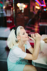 Blonde adorable female in american classic retro cafe sitting and smiling