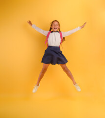 Fototapeta na wymiar Young girl student jumps high happy for the promotion. Yellow background
