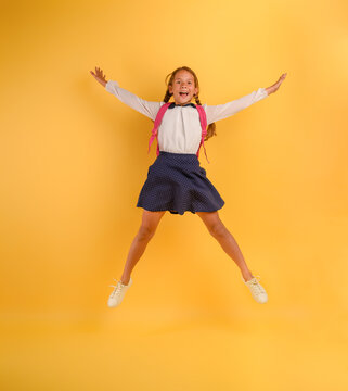 Young girl student jumps high happy for the promotion. Yellow background