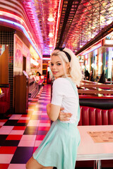 Blonde adorable female in american classic retro cafe standing and flirting