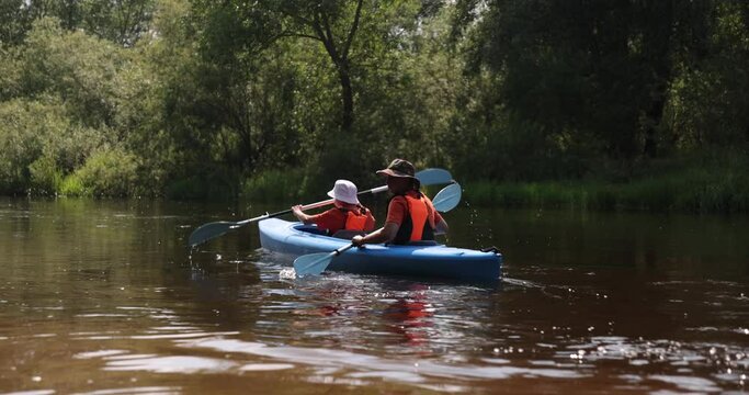 Kayaking on the River. Boy and man tourists kayaking down the river, teamwork