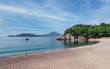Fototapeta na wymiar Cozy sandy beach in Montenegro on Adriatic seashore in Budva Riviera. Summer holidays vacation.