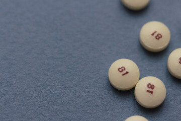 scattered low dose 81 milligrams aspirin on a slate blue gray background with a low depth of field,...