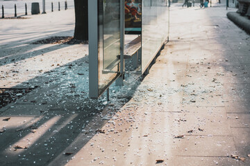 Broken glass at the bus stop. Public transport station vandalised by smashing the glass windows....