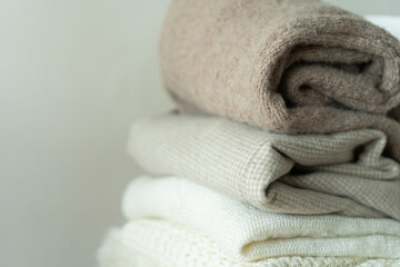 Pile of knitted sweaters. Warm background, knitwear, space for text. Autumn winter concept. Background with sweaters