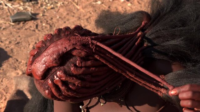 Closeup shot of Himba woman doing her hair at traditional Himba village near Kamanjab in northern Namibia, Africa.