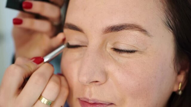 women do make-up, paint the eyelids on the eyes with a makeup brush. 
