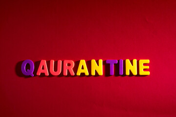 Completing quarantine words. Quarantine word made from colourful plastic baby development blocks. Red background