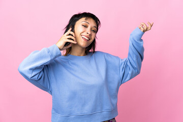 Young Uruguayan woman over isolated pink background keeping a conversation with the mobile phone with someone