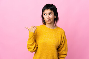 Young Uruguayan woman over isolated pink background unhappy and pointing to the side