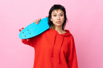 Young Uruguayan woman over isolated pink background with a skate