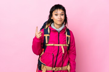 Young mountaineer girl with a big backpack over isolated pink background pointing with the index finger a great idea