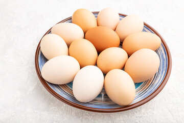 Pile of colored eggs on plate on a gray concrete background. side view.