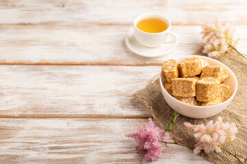 Traditional turkish delight (rahat lokum) with cup of green tea on a white wooden background. side view, copy space.