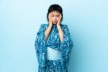 Young woman wearing kimono over isolated blue background with headache
