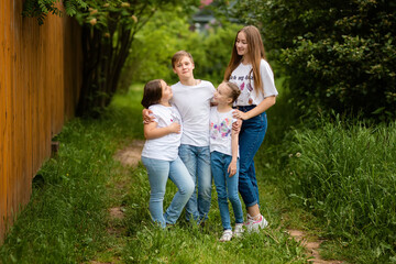 Fototapeta premium Four happy, smiling children play on the grass on a warm summer day. Good friends spend their holidays together. Family values, loving brothers and sisters.