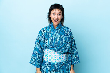 Fototapeta premium Young woman wearing kimono over isolated blue background with surprise facial expression