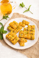 Traditional iranian dessert sohan with glass of green tea on a gray concrete background, side view, close up.