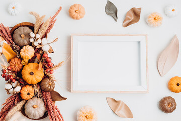 Rustic mockup with empty frame and autumn table decoration.  Floral interior decor for fall holidays with handmade pumpkins. Holiday greeting card. Flatlay, top view.