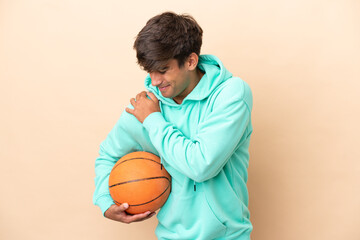 Handsome young basketball player man isolated on ocher background suffering from pain in shoulder...