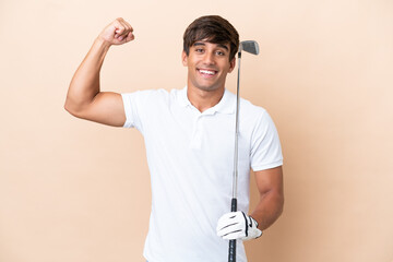 Young golfer player man isolated on ocher background doing strong gesture